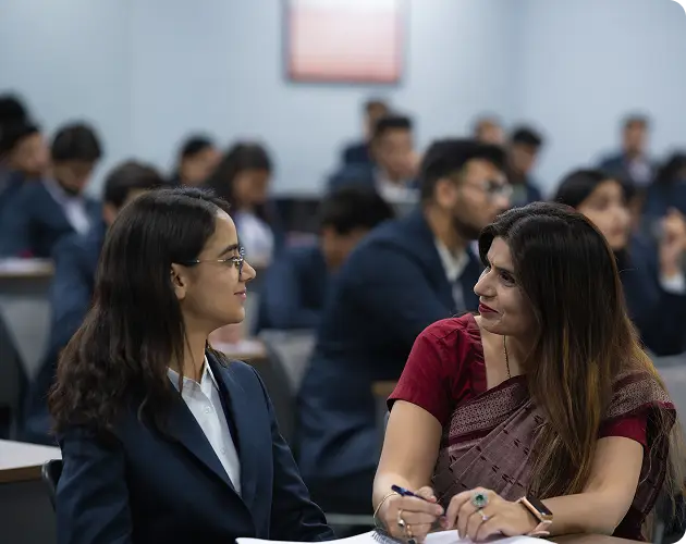 A professor at Narayana Business School assisting a student during a lecture.