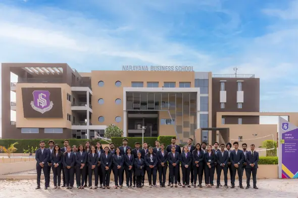 Group of MBA students in formal suits standing in front of the Narayana Business School campus building, representing professionalism and academic excellence.